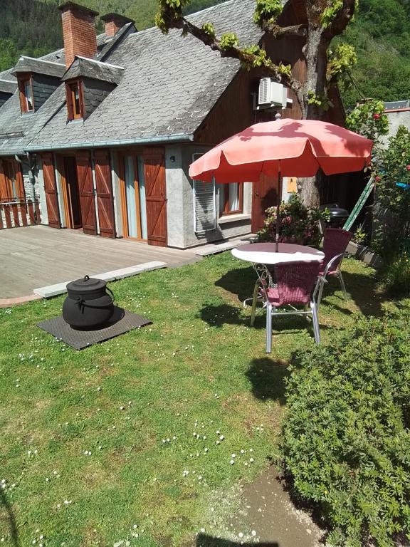 - une table et des chaises avec un parasol dans la cour dans l'établissement petit gîte de montagne avec jardin et terrasse, à Cazaux-Layrisse