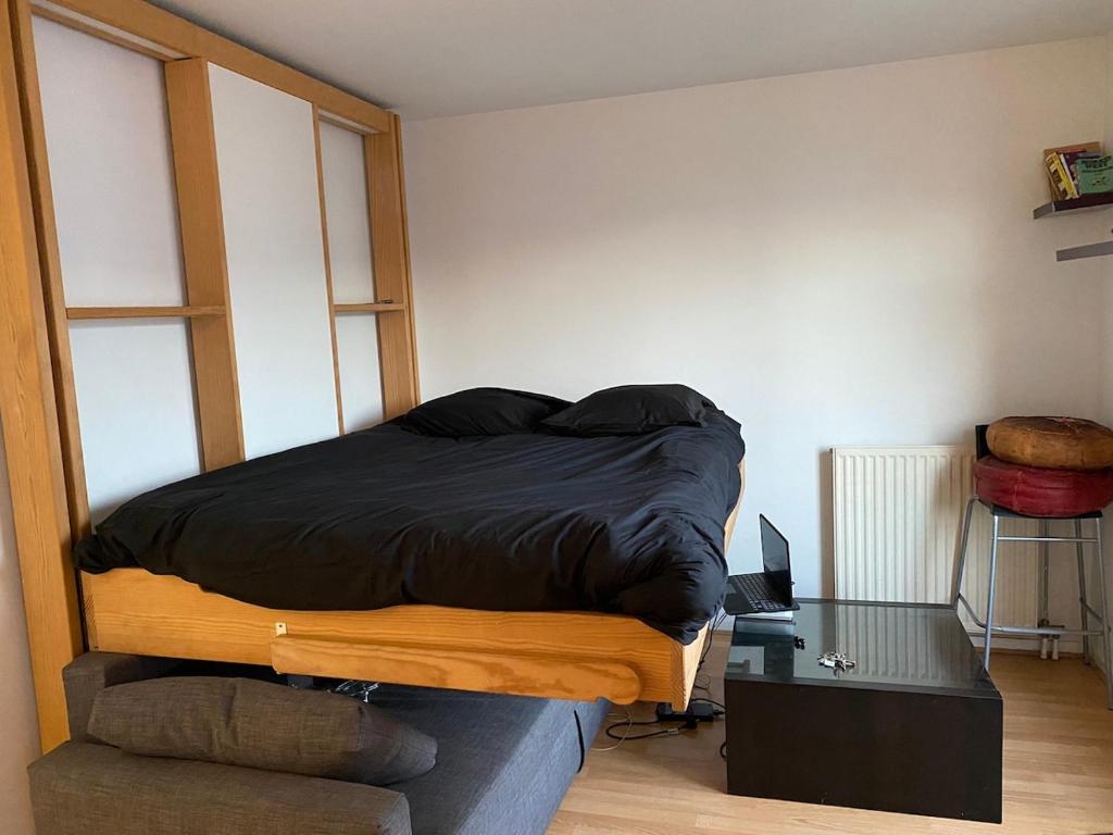 クリシーにあるPetit paradisの部屋には黒い掛け布団が敷かれたベッドと机がある