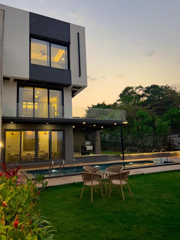 a house with chairs and a table in the yard at Aviran Villa 5BHK - Jacuzzi House in Lonavala