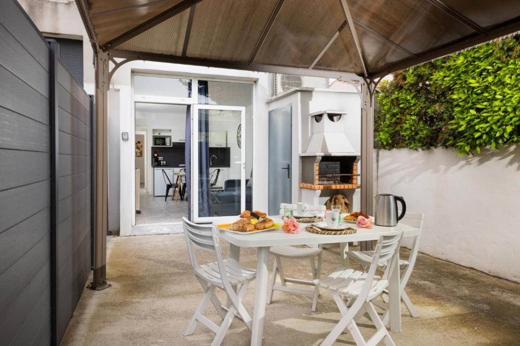 - une table et des chaises blanches sur la terrasse dans l'établissement L'atelier De La Cite - Parking Gratuit Sécurisé, à Carcassonne