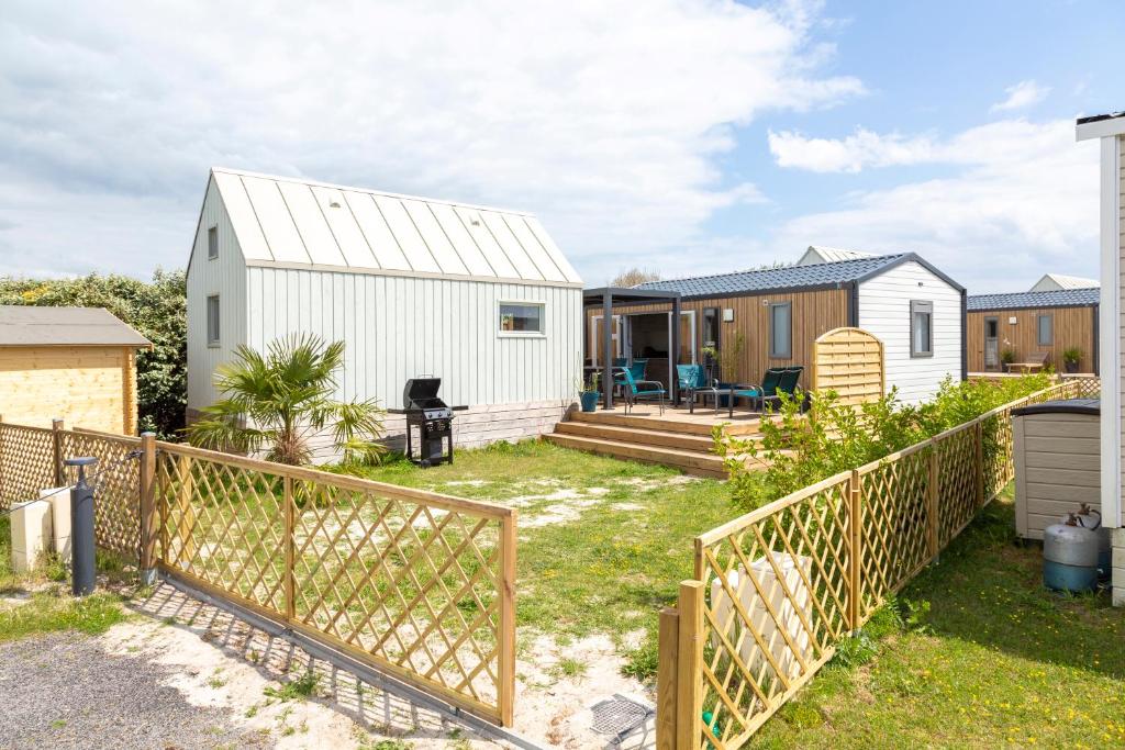 une arrière-cour avec une maison blanche et une clôture dans l'établissement Mobilhome et chalet Guilvinec, au Guilvinec