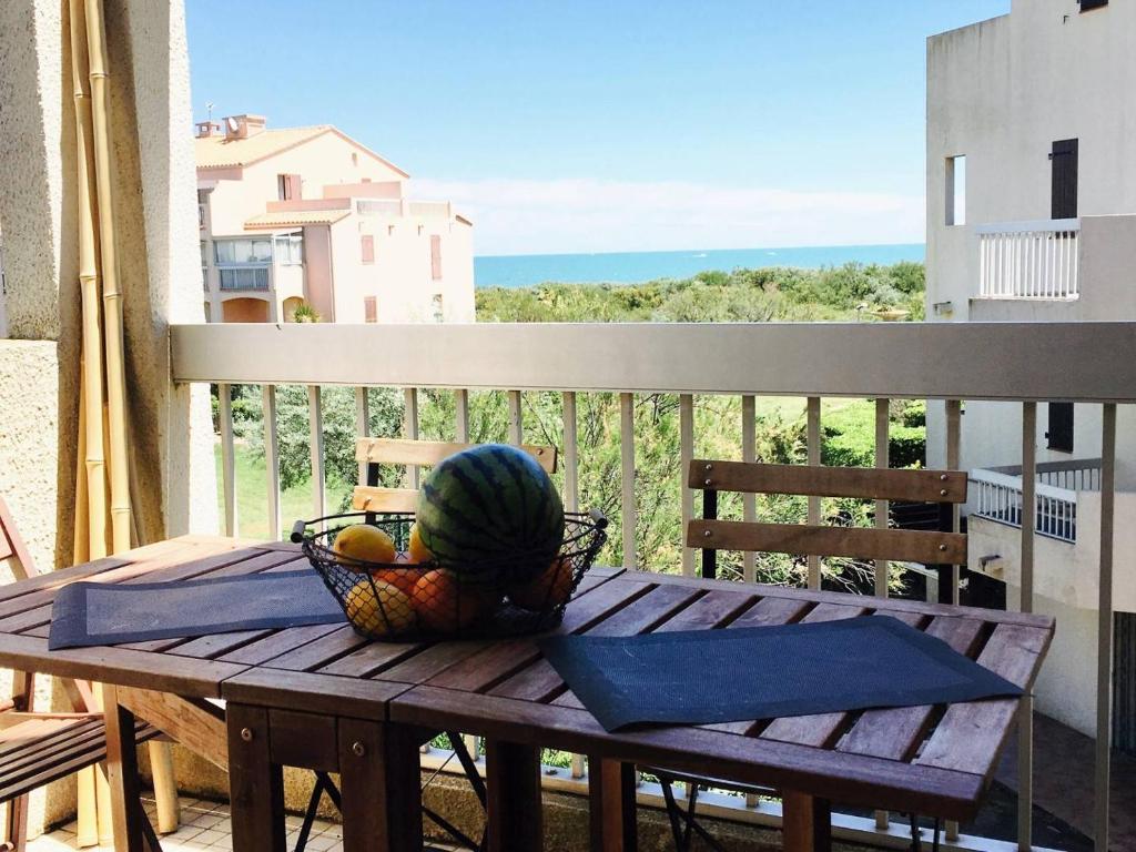 une table en bois avec une corbeille de fruits sur un balcon dans l'établissement Piscine, plage et vue mer pour ce beau T3 rénové avec goût - 6FR324, à Saint Cyprien Plage