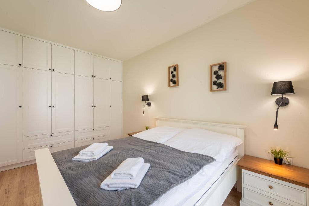 a bedroom with a white bed with two towels on it at Seaside Sun Seasons 24 Apartments in Pogorzelica with Parking by Noclegi Renters in Pogorzelica