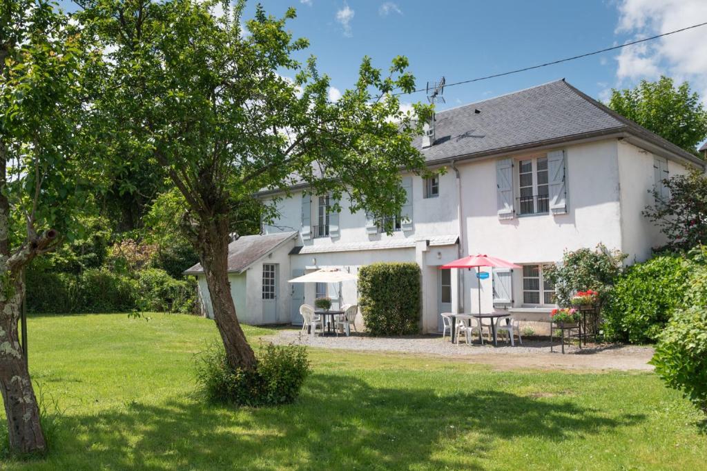 a white house with a table and chairs in the yard at La Maison des Vacances in Argelès-Gazost