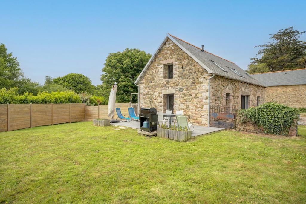une maison en pierre avec une cour avec des chaises et une planche de surf dans l'établissement Erquy Les Hirondelles, à Erquy