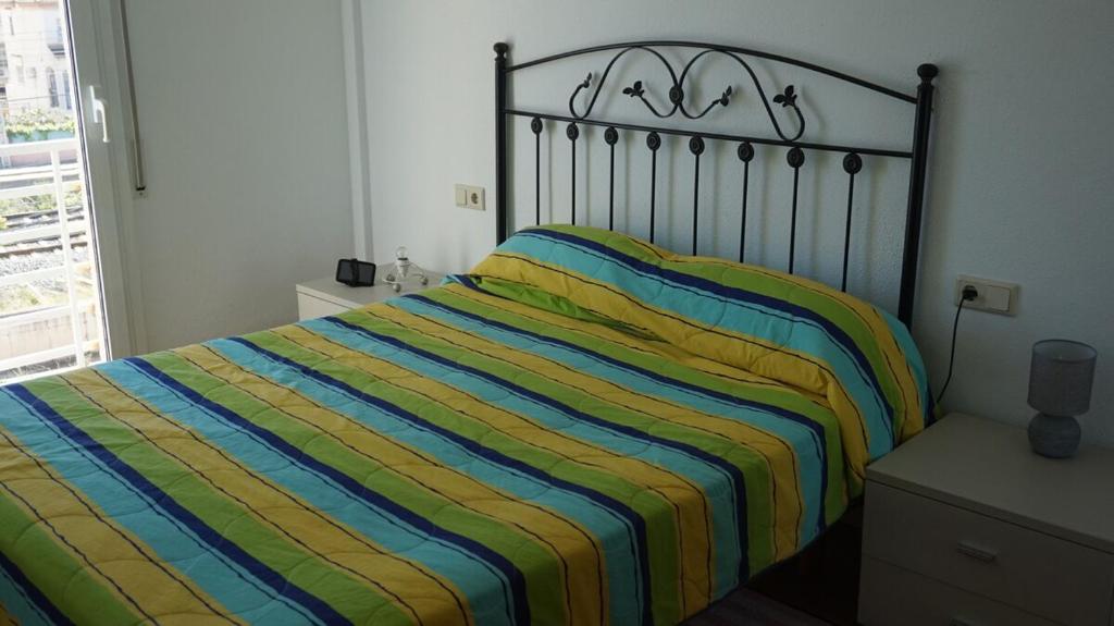 a bedroom with a bed with a striped blanket at Imperatore Apartment in Cunit