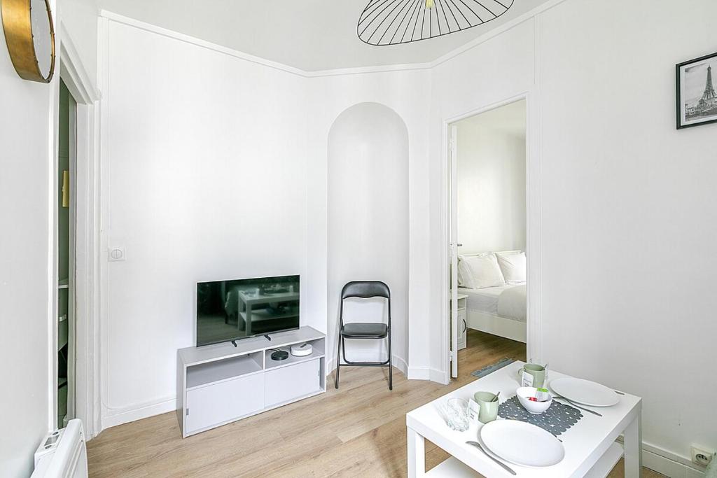 un salon blanc avec une télévision et une table dans l'établissement Nid douillet pour deux dans le Paris des artistes, à Paris
