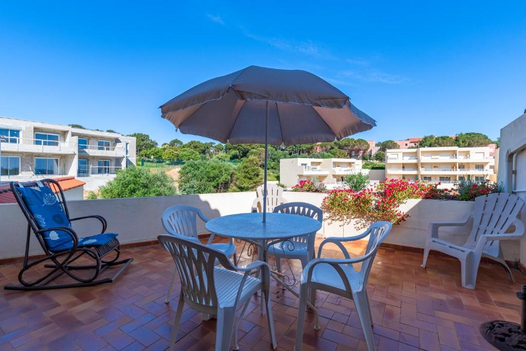 un patio avec une table, des chaises et un parasol dans l'établissement Filetta - Charmant studio climatisé, à Lumio