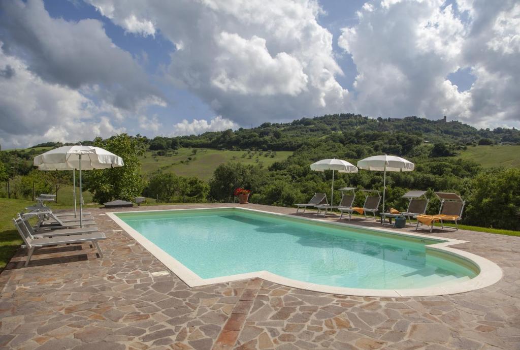 Una piscina con sillas y sombrillas en un patio. en Agriturismo Podere Il Colle, en Radicondoli