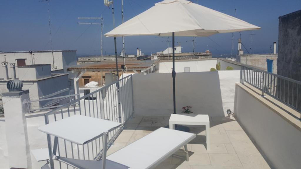 a patio with tables and an umbrella on a roof at Silvia House - Vb Vacanze Ostuni in Ostuni