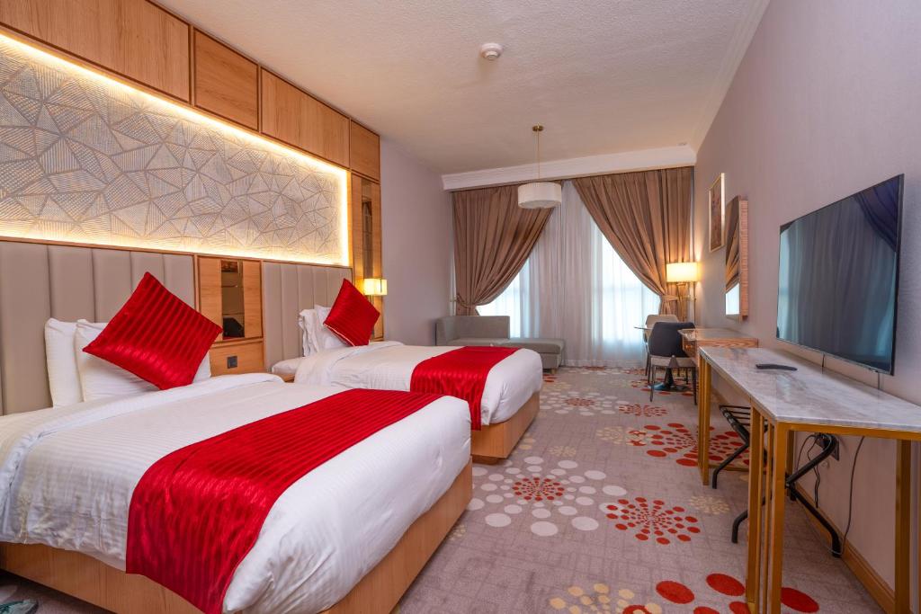 een hotelkamer met twee bedden en een flatscreen-tv bij La Zona Continental Hotel in Dubai