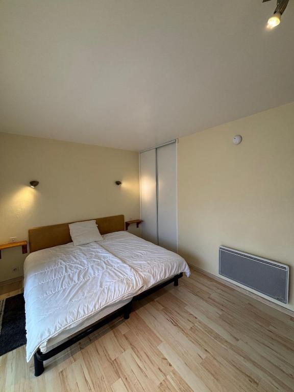 Cette chambre comprend un lit avec des draps blancs et du parquet. dans l'établissement StudiosMichel apt 16 balcon thermes 400m à pied, à Cazaubon