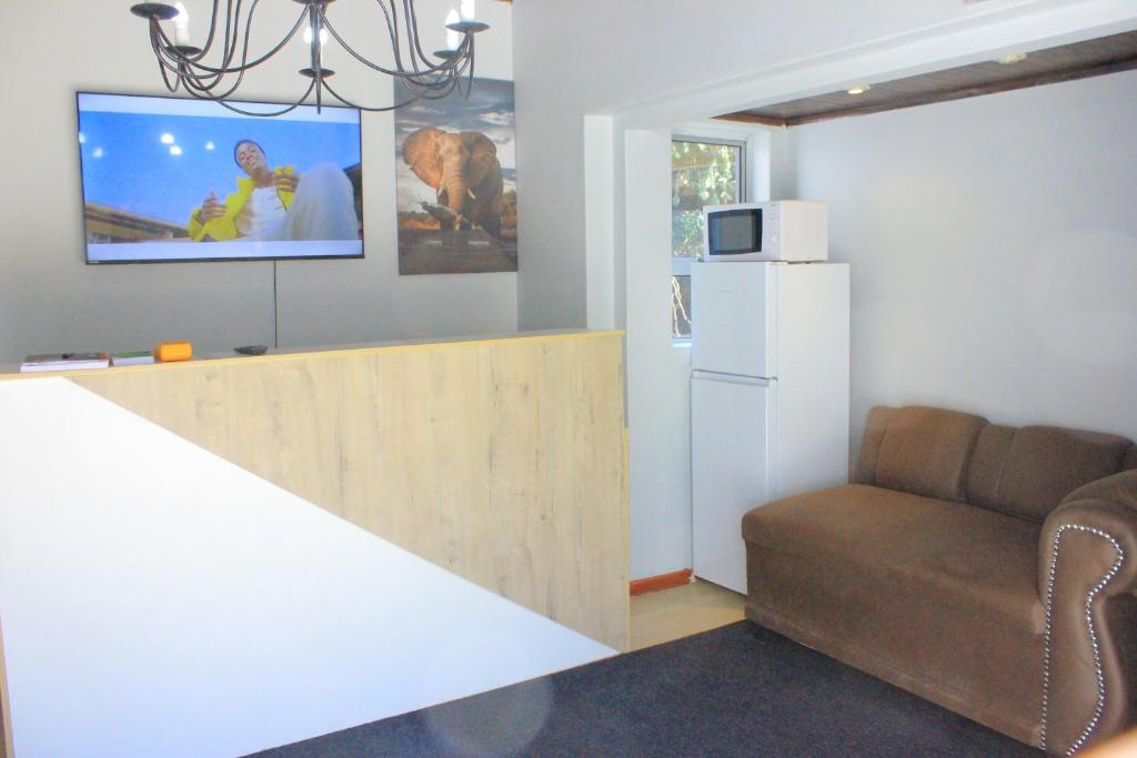 un soggiorno con divano e frigorifero bianco di Fargon Guest House a Polokwane