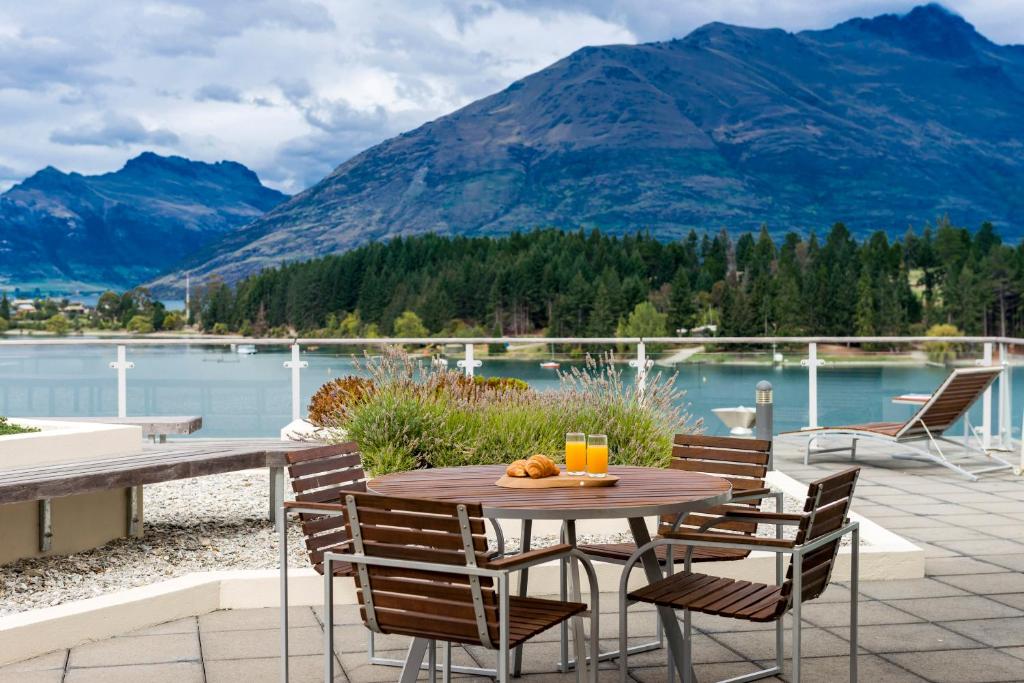 a table and chairs on a patio with a view of a lake at Oaks Queenstown Club Suites in Queenstown