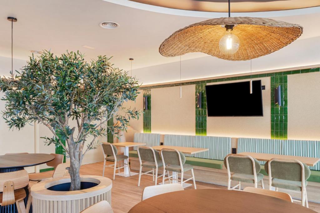 una sala de espera con mesas, sillas y TV en B&B HOTEL Murcia, en Murcia