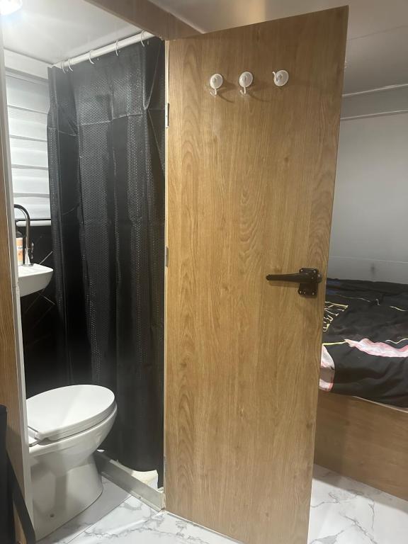 ein Badezimmer mit einem WC und einer Holztür in der Unterkunft קרוואן על הים in Eilat