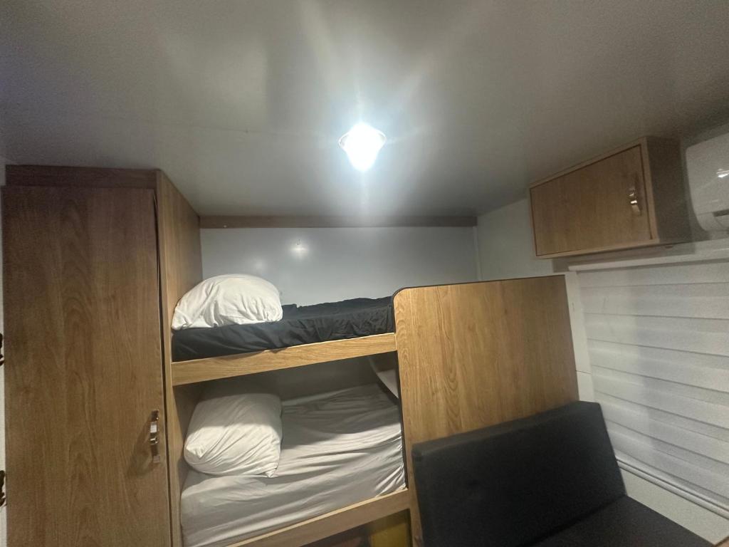 ein kleines Zimmer mit 2 Etagenbetten und einem Stuhl in der Unterkunft קרוואן על הים in Eilat