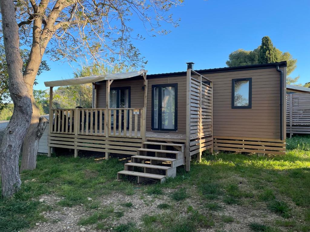 une cabane en rondins avec une véranda et un arbre dans l'établissement mobil-home 3 chambres calme et tout équipé à carry-le-rouet proche piscine avec toboggans pataugeoire et animations peu de vis à vis terrasse barbecue paddle bodyboards accès libre aux activités du camping lou soulei commerces et plage à proximité, à Carry-le-Rouet