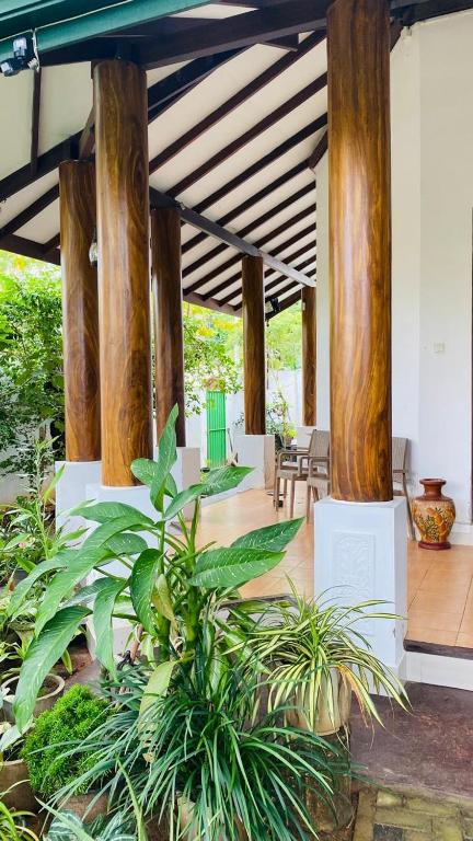 a lobby with wooden columns and plants in a building at catherine villa in Ja-Ela