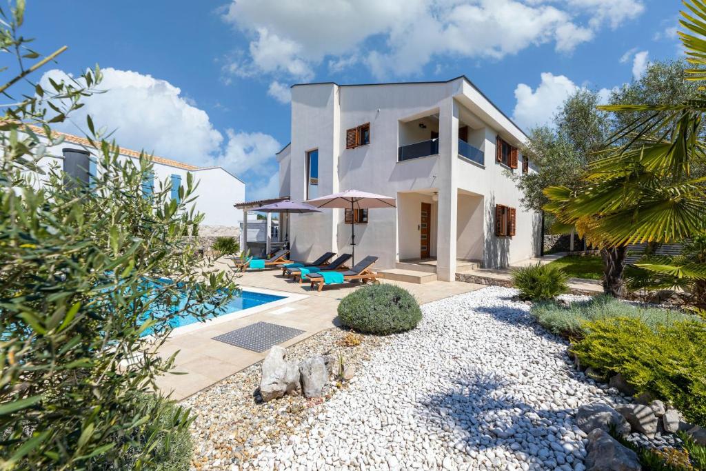 a white house with a pool and a yard at Villa Andante Malinska in Malinska