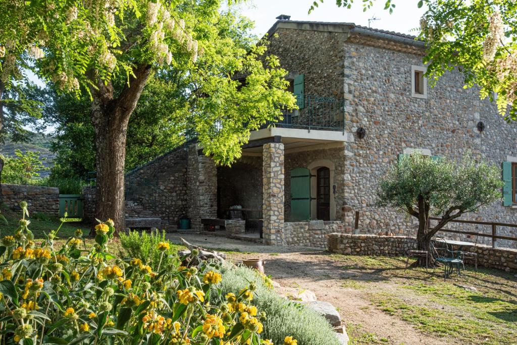 een stenen huis met een boom en bloemen bij Les Cezennes in Saint-Ambroix