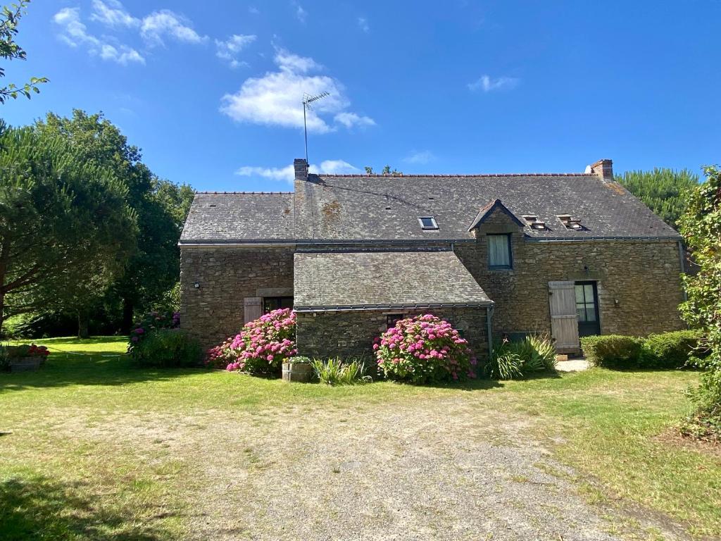 une maison en briques avec des fleurs roses dans la cour dans l'établissement Fleur de Sel, longère au calme , proche mer et plages, à Assérac