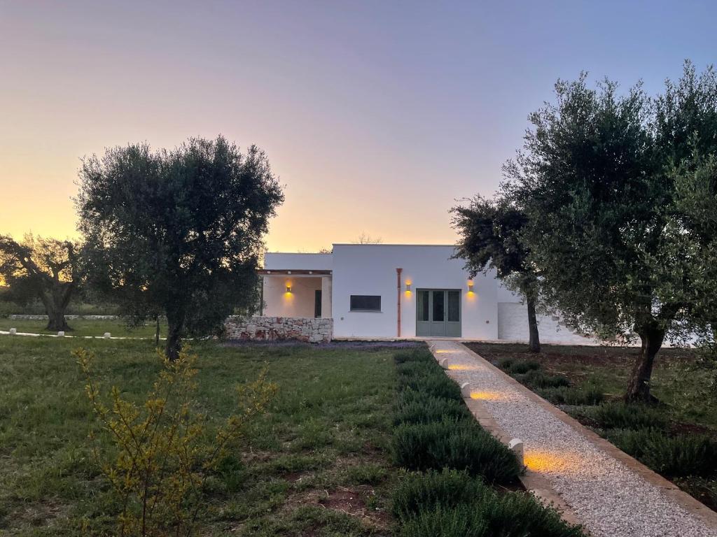 une maison blanche avec des arbres devant dans l'établissement Villa Karbina, à Carovigno