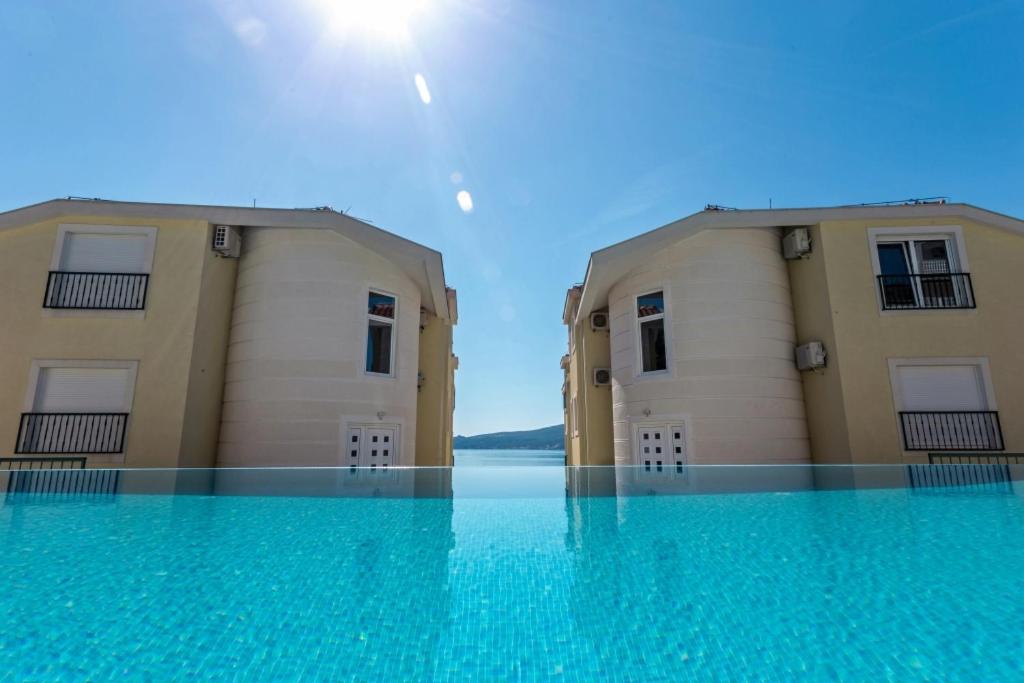 two buildings with blue water in front of them at Adriadome Apartments in Bijela