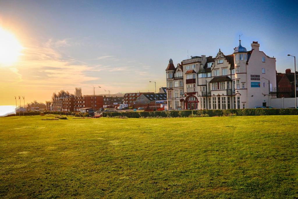 um grande edifício num campo com o sol no céu em Cliftonville Hotel em Cromer