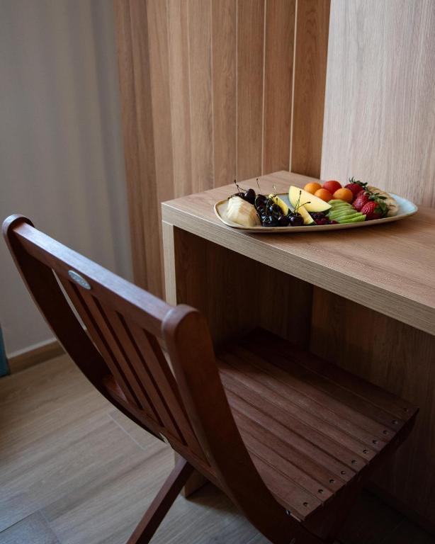 a plate of fruit sitting on a table with a chair at Nireus Hotel in Symi