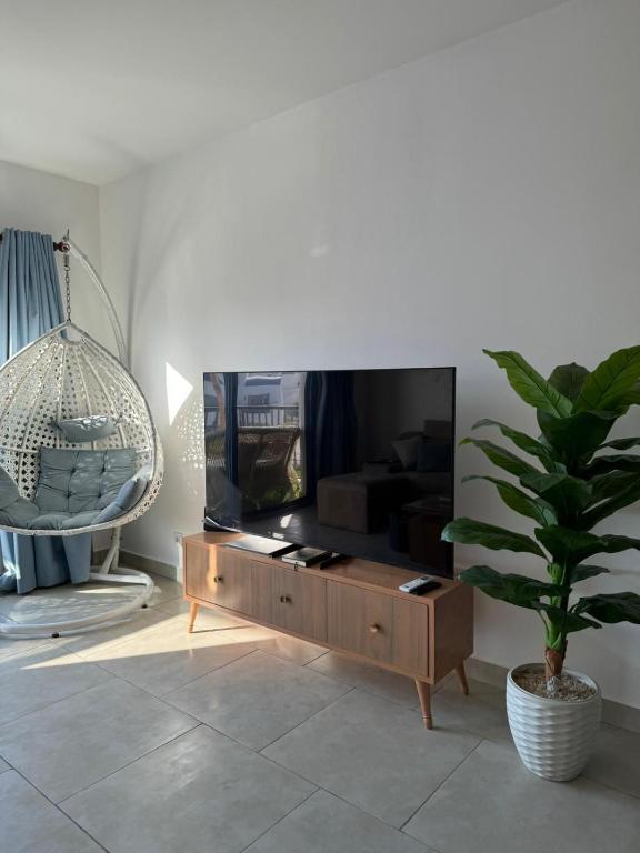 a living room with a tv and a potted plant at Marassi in Dawwār Abū Maḩrūs
