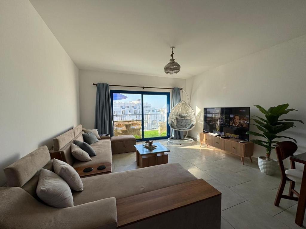 ein Wohnzimmer mit Sofa und Fernseher in der Unterkunft Marassi in Dawwār Abū Maḩrūs