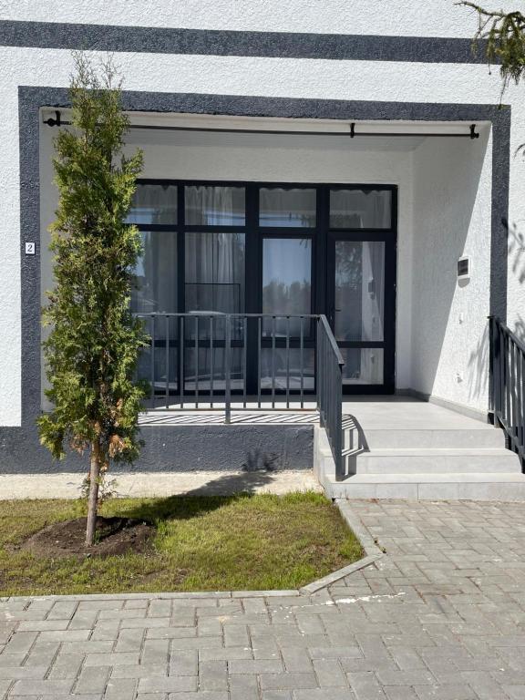 a building with a door with a staircase and a tree at Коттедж в ЦО Атлантис in Chon-Sary-Oy
