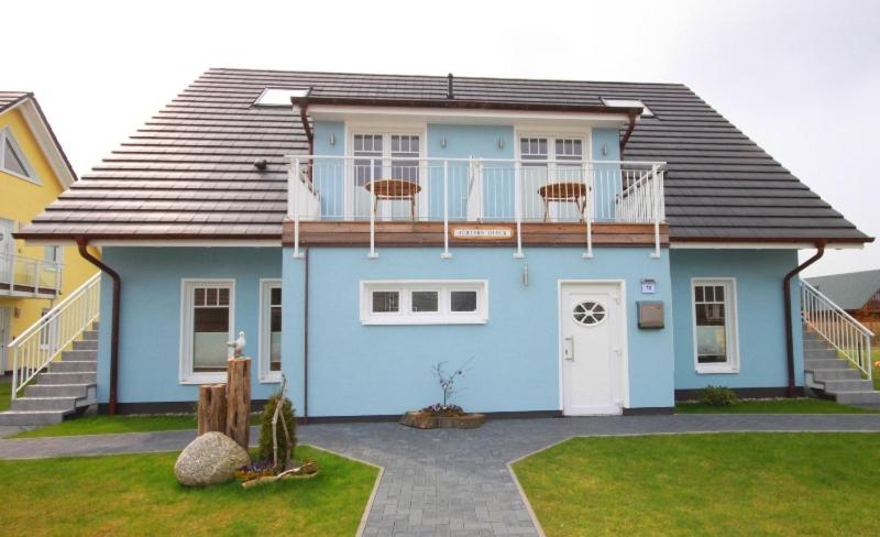 a blue house with a balcony on top of it at Achtern Diek - Ferienwohnungen in Börgerende-Rethwisch