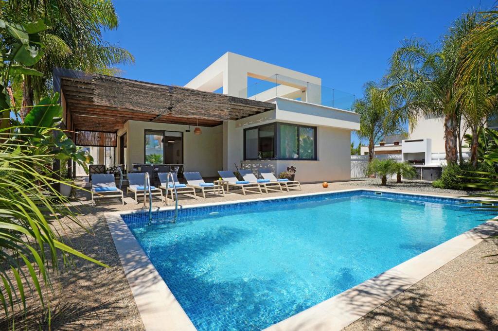 a villa with a swimming pool in front of a house at Villa Evergreen - 3bed Bungalow large pool in Protaras