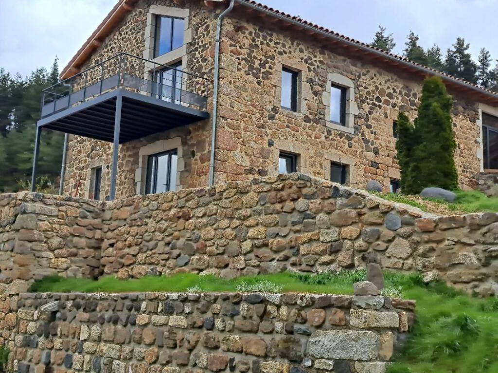 a stone house with a balcony on top of a stone wall at La Clef des songes in Lafarre