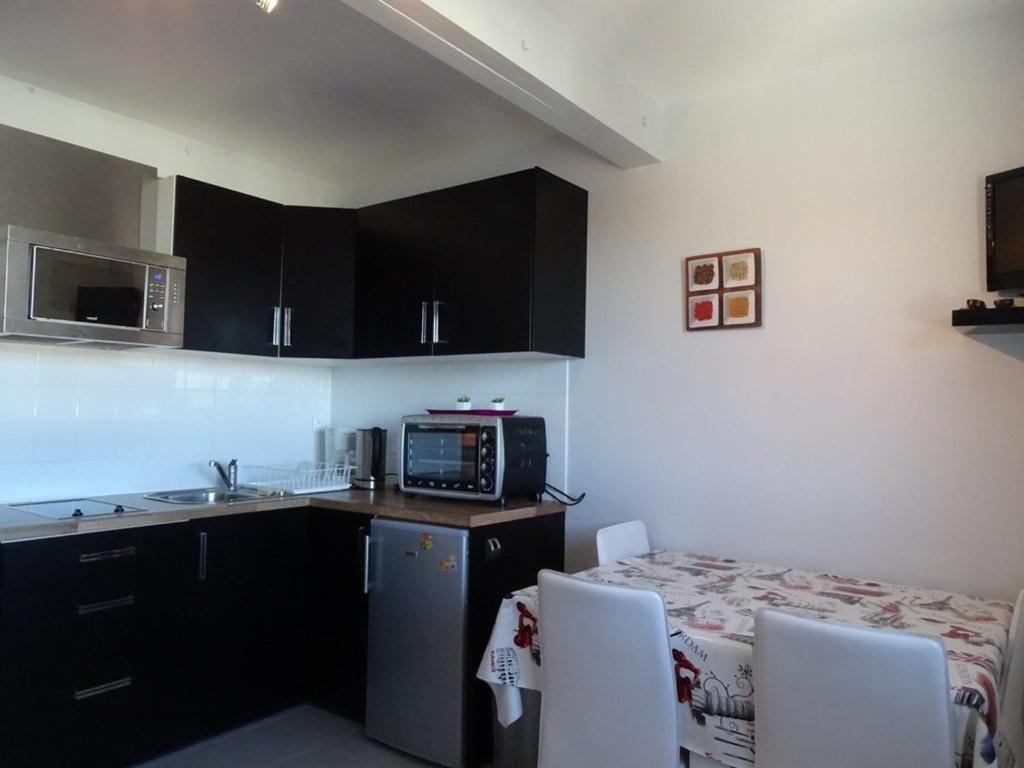 une cuisine avec des placards noirs, une table et un four micro-ondes dans l'établissement Studio cosy 4 pers, ski aux pieds, casier à skis, parkings gratuits, équipement complet inclus. - FR-1-602-4, à Arette