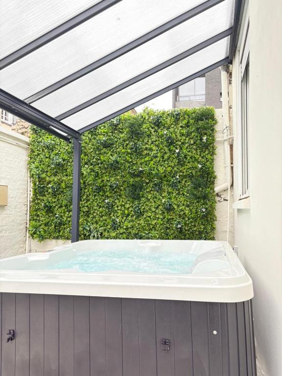 a jacuzzi tub on a patio with a hedge at Maison moderne en plein centre ville du Havre avec jacuzzi et parking gratuit in Le Havre