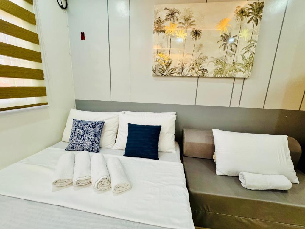 a bed with white sheets and blue pillows at Full House Santa Ana in Sampong