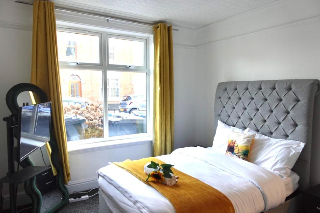 ein Schlafzimmer mit einem Bett mit einem großen Fenster in der Unterkunft Kyoto Central I 4 BDR House I 50 inch Smart TVs in Rooms I Large Spacious Rooms I Refurbished I Derby City Centre in Derby