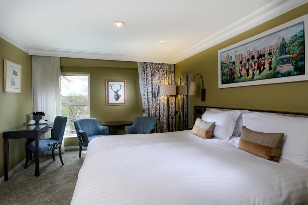 a hotel room with a large bed and a desk at Castle Hotel Windsor in Windsor