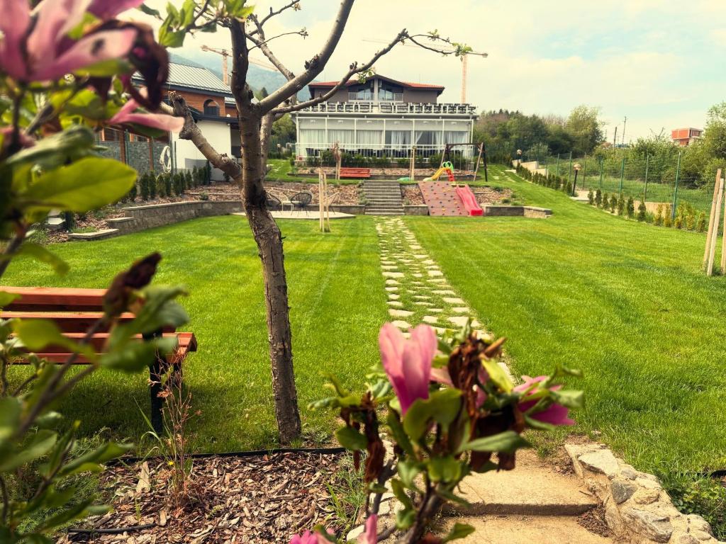 a park with a building in the background with pink flowers at Villa YoSi - rooms in Sapareva Banya