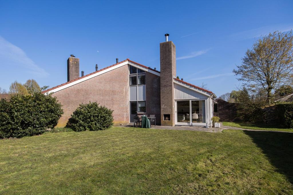 a brick house with two chimneys on top of a yard at Kiekendief I Gerenoveerd Huisje in Scandinavische Stijl in Zwiggelte