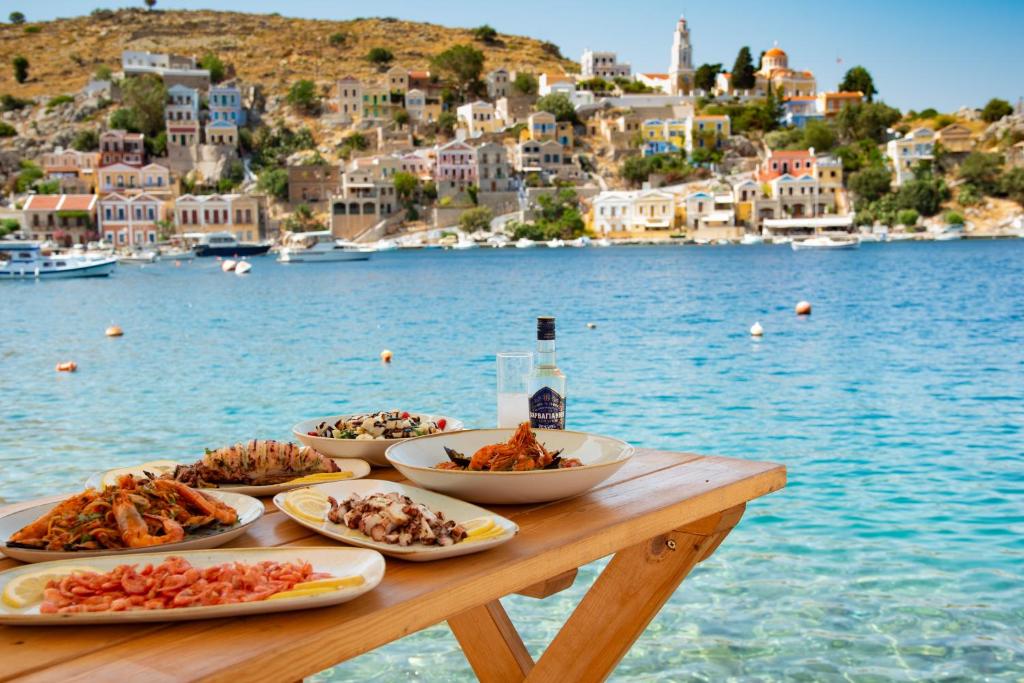 a table with plates of food on a table near the water at Nireus Hotel in Symi