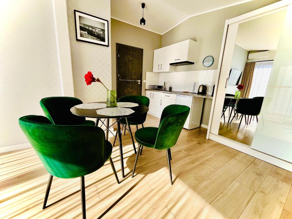 a dining room with a table and green chairs at Apartamenty BLAST nad morzem Chłopy in Chłopy