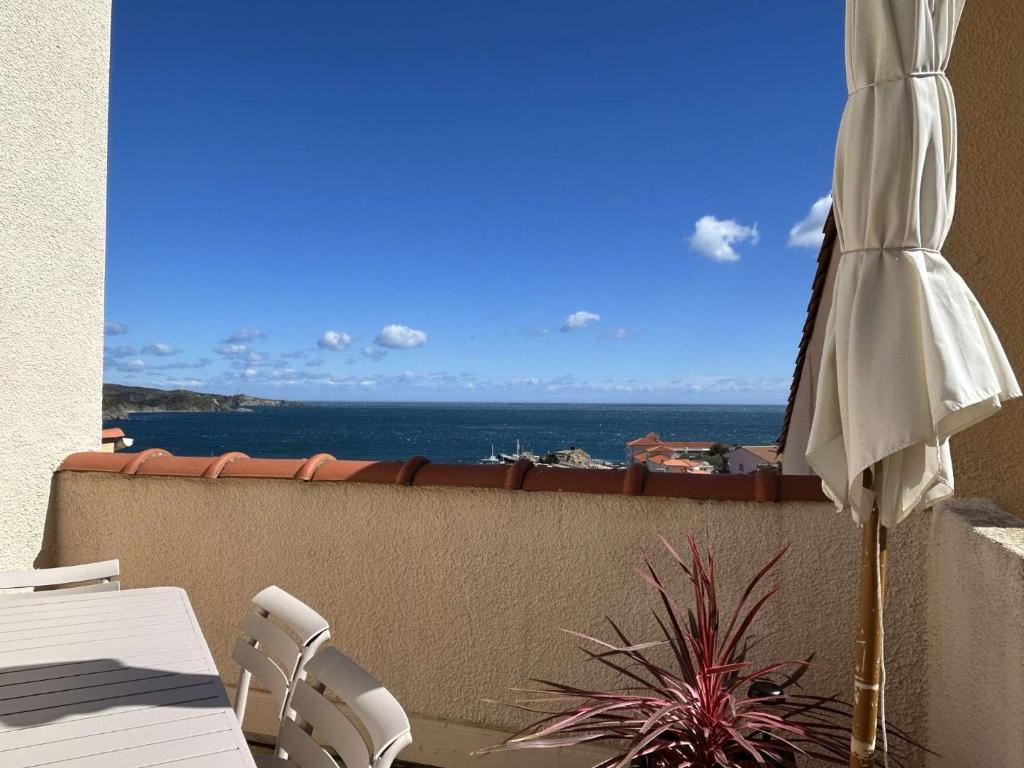 un parasol et des chaises sur un balcon avec l'océan dans l'établissement T4 Duplex - 6 Couchages - BANYULS SUR MER BN030-E22, à Banyuls-sur-Mer