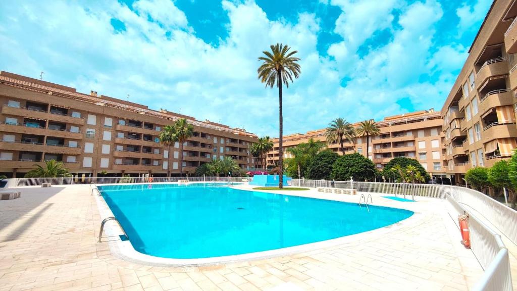 a swimming pool with a palm tree and buildings at Tirolina by Edeal HOMES in Denia