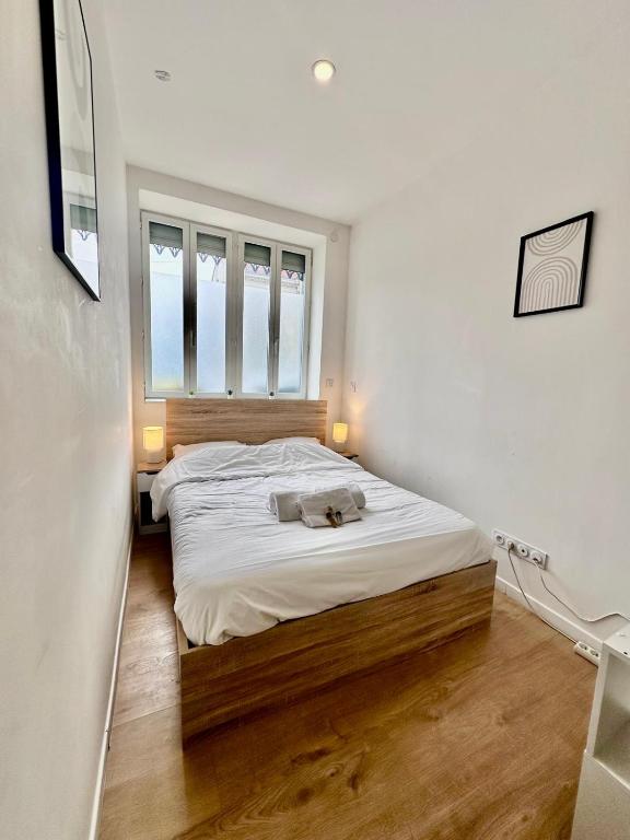 Cette petite chambre comprend un lit avec des draps blancs et une fenêtre. dans l'établissement L'Alsacien - Villeurbanne - Métro A et B, à Villeurbanne