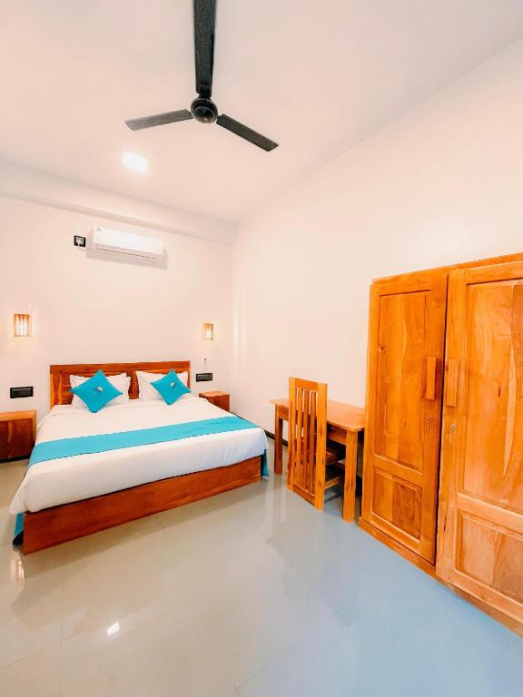 a bedroom with a bed and a wooden desk at Peak Bay Resort in Arugam Bay