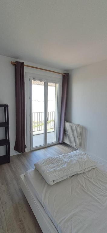 un lit blanc dans une chambre avec une grande fenêtre dans l'établissement Chez Bibi, à Saint-Georges-de-Didonne